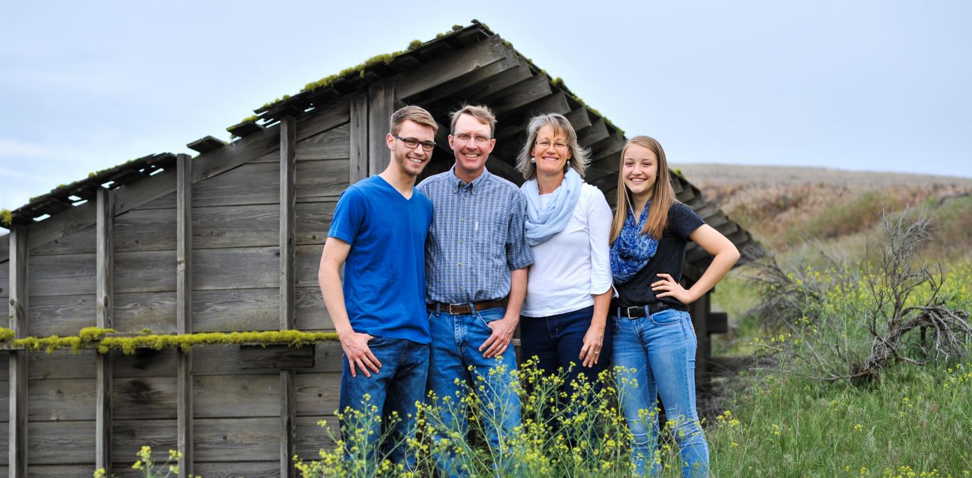 Farming family standing in front of barn