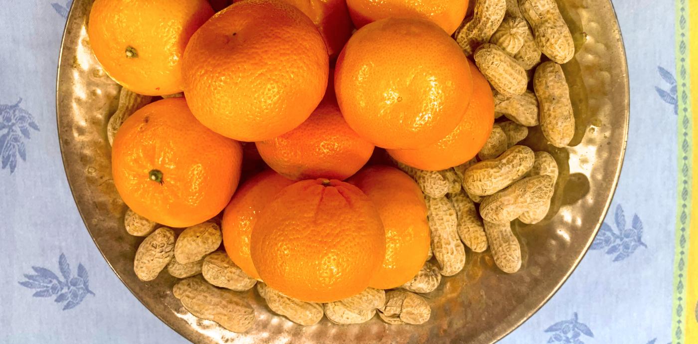 a large gold serving bowl filled with peanuts and clementines