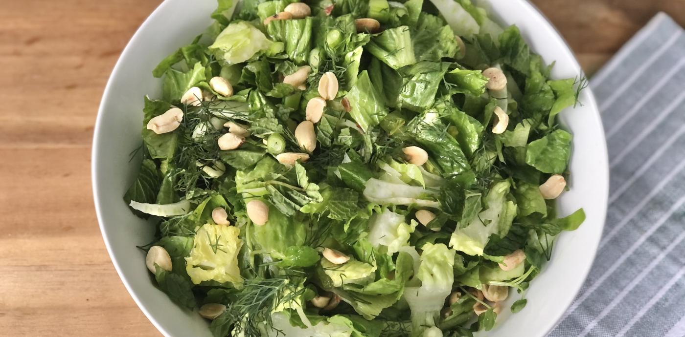 green salad with peanuts in a white bowl