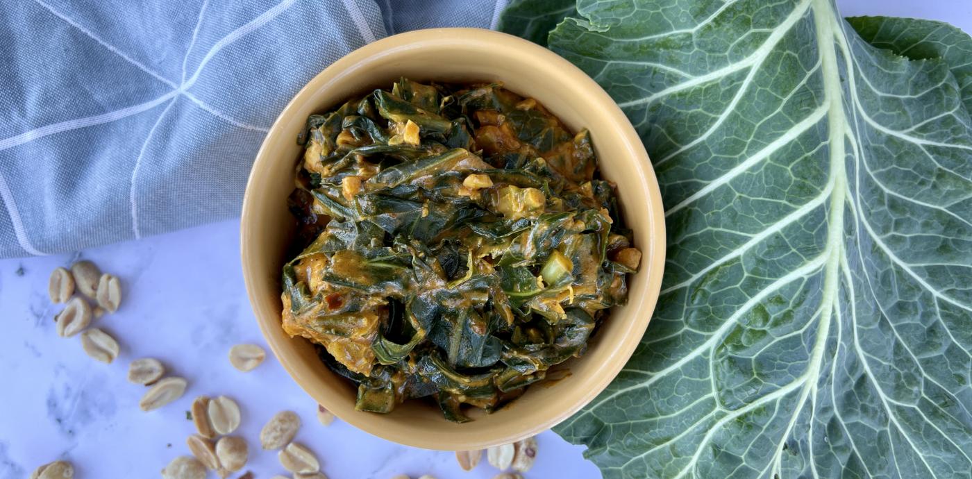 a bowl of cooked greens with a large collard green leaf nearby