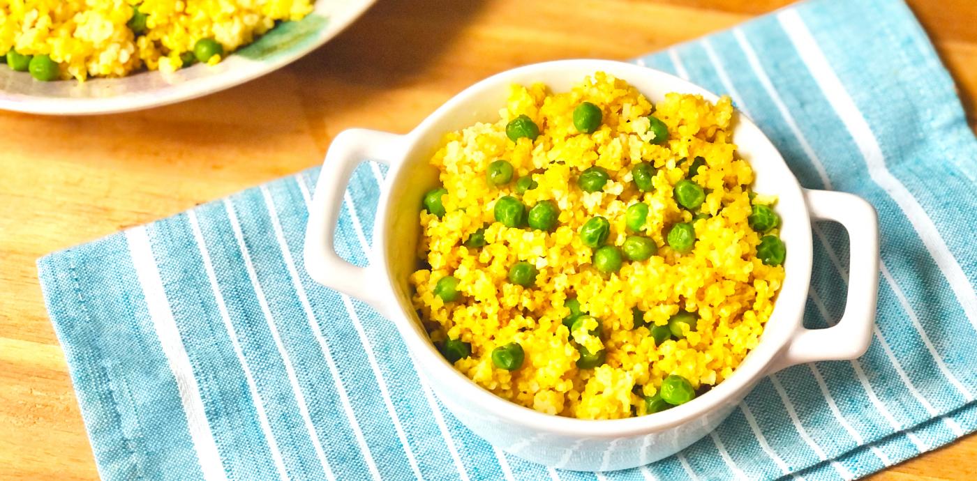 a dish with bright yellow millet garnished with peas and spices