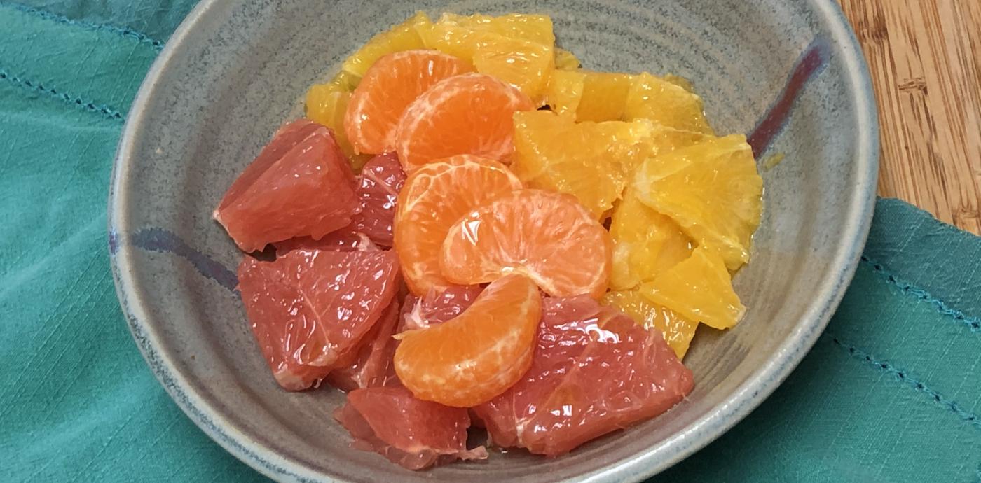 Mixed citrus slices in a bowl on a blue napkin