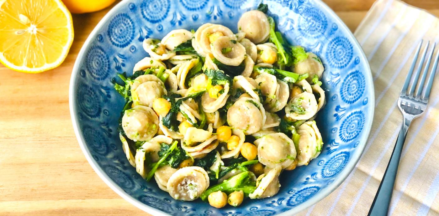 a blue dish filled with whole grain orecchiette pasta and vegetables