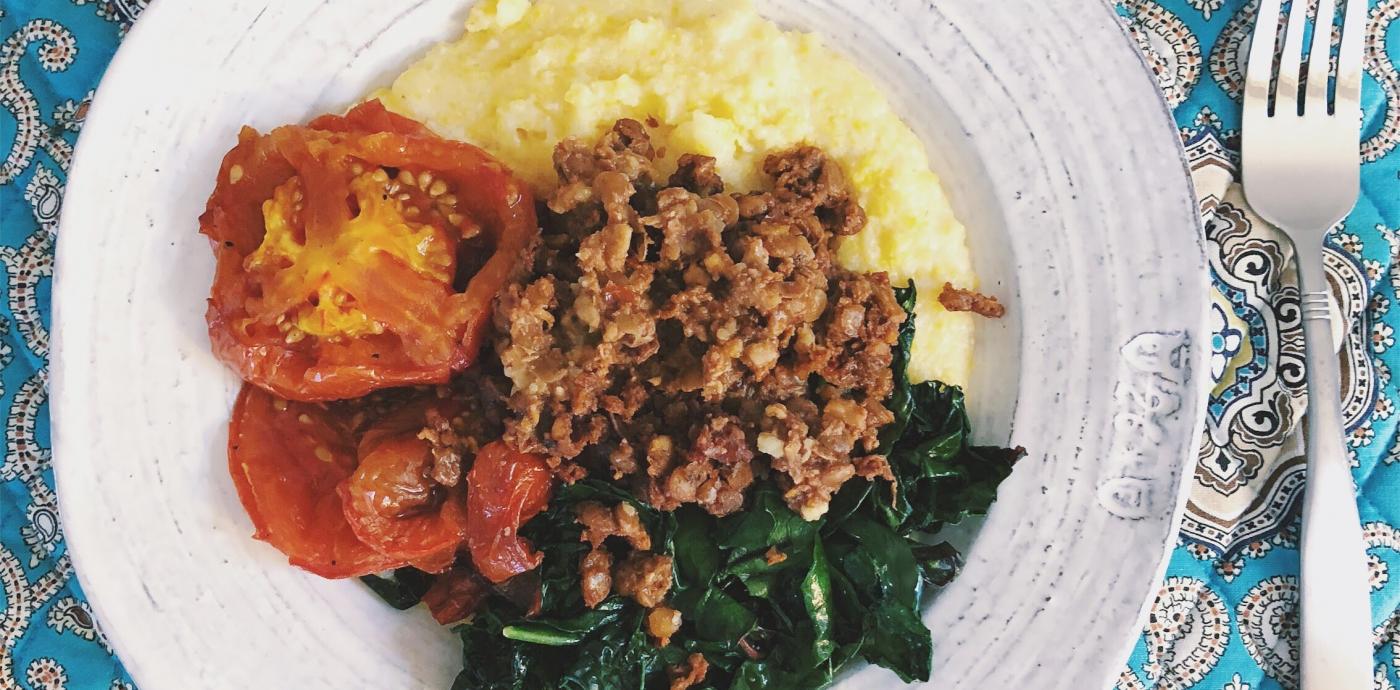 bowl on a placemat with polenta, roasted tomatoes, greens, and chorizo