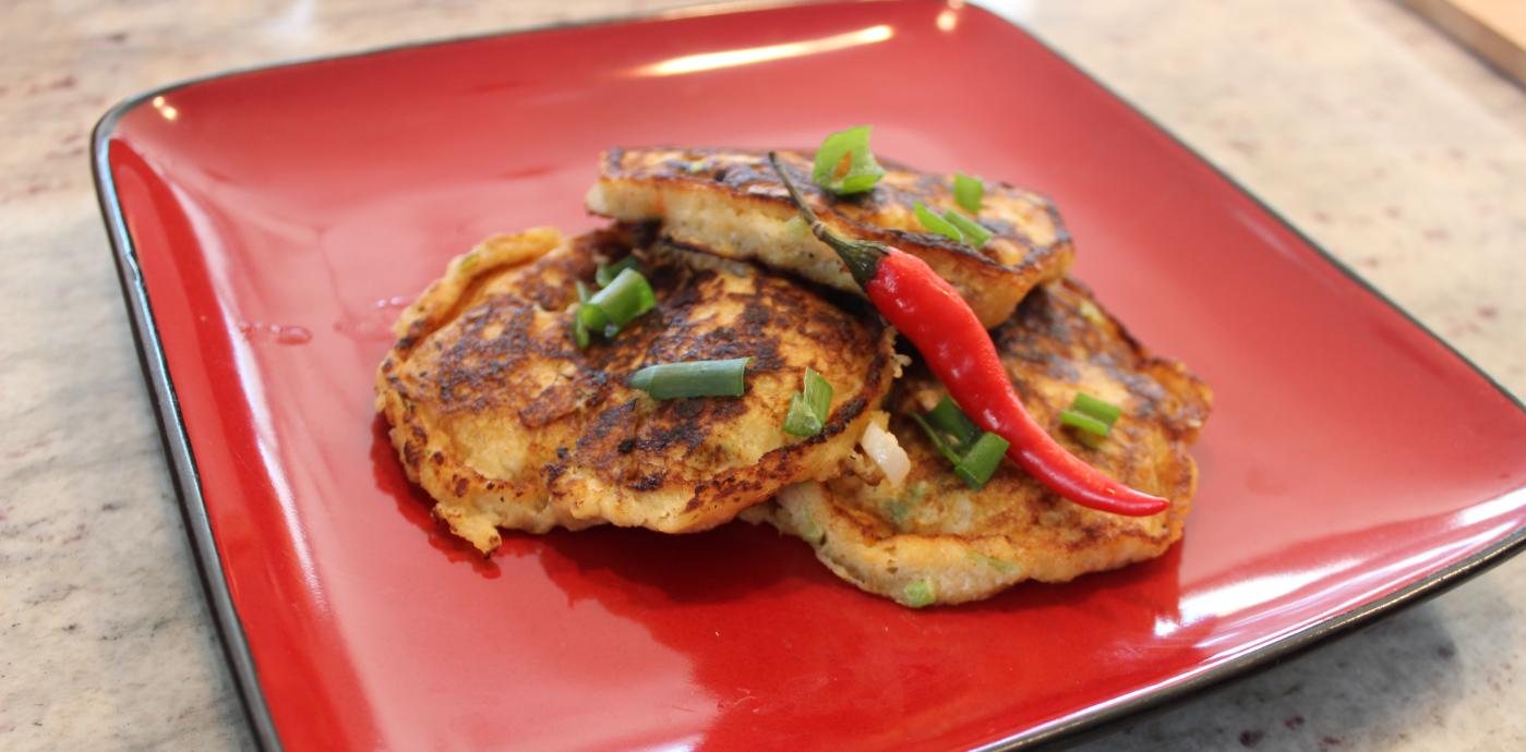 plantain pancakes on a red plate garnished with a chile pepper