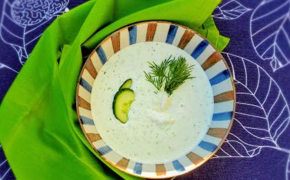 Bowl of white soup with cucumber and dill garnish