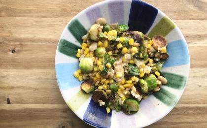 a colorful bowl filled with corn, brussels sprouts, and beans