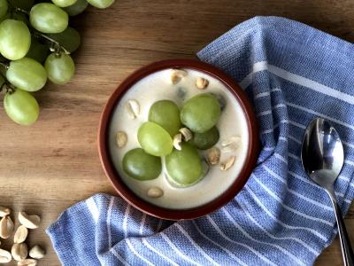 creamy soup topped with green grapes on a wooden surface