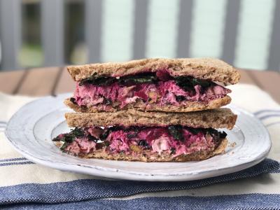 sandwich with beet filling and whole grain bread on a plate outdoors
