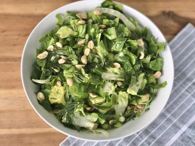 green salad with peanuts in a white bowl