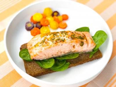 salmon atop a piece of rye toast with carrots on the side
