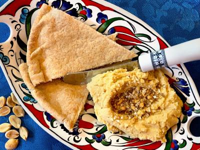 hummus and whole wheat pita in a colorful Mediterranean style dish