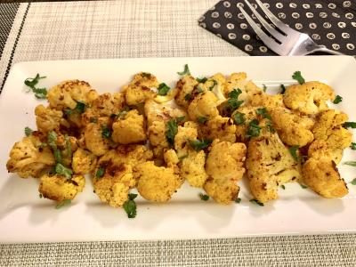 cauliflower florets tinted yellow with spices atop a white platter