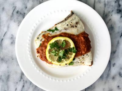 white fish covered in red sauce on a white plate