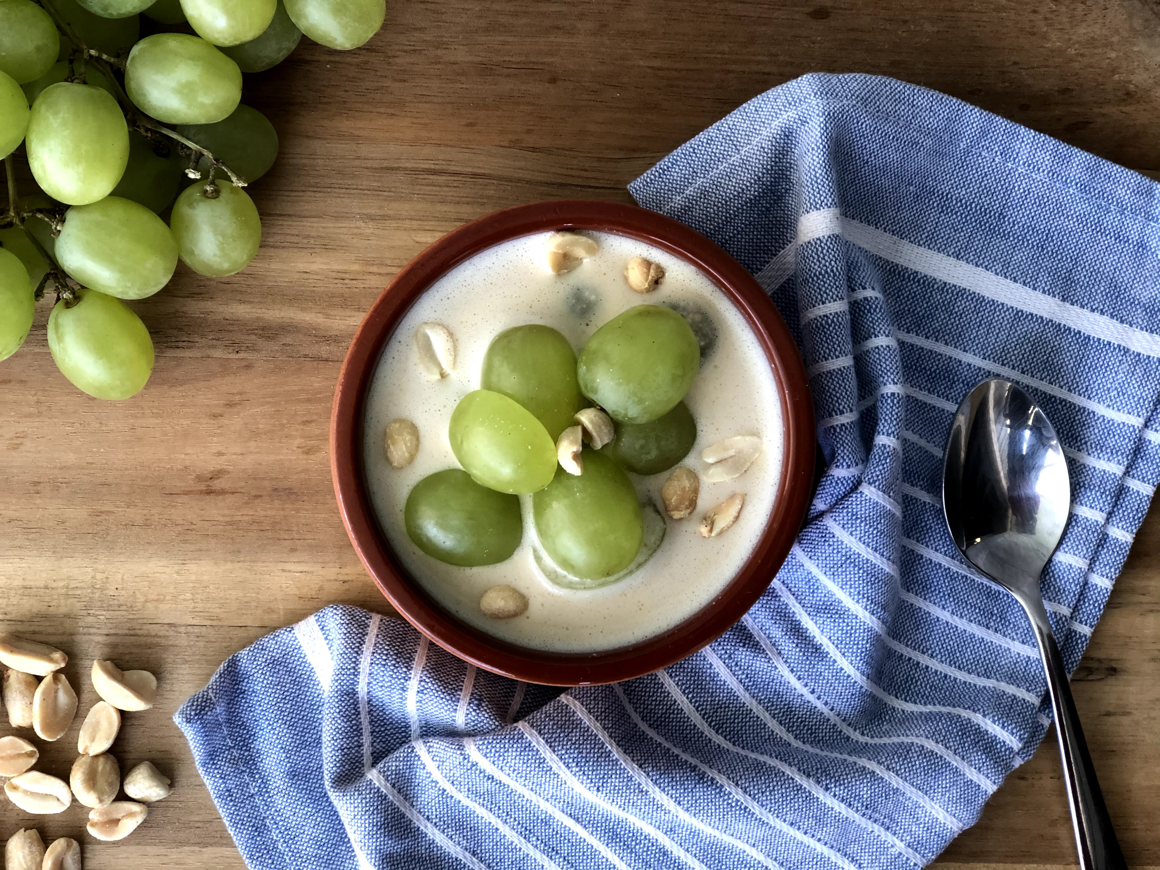 creamy soup topped with green grapes on a wooden surface