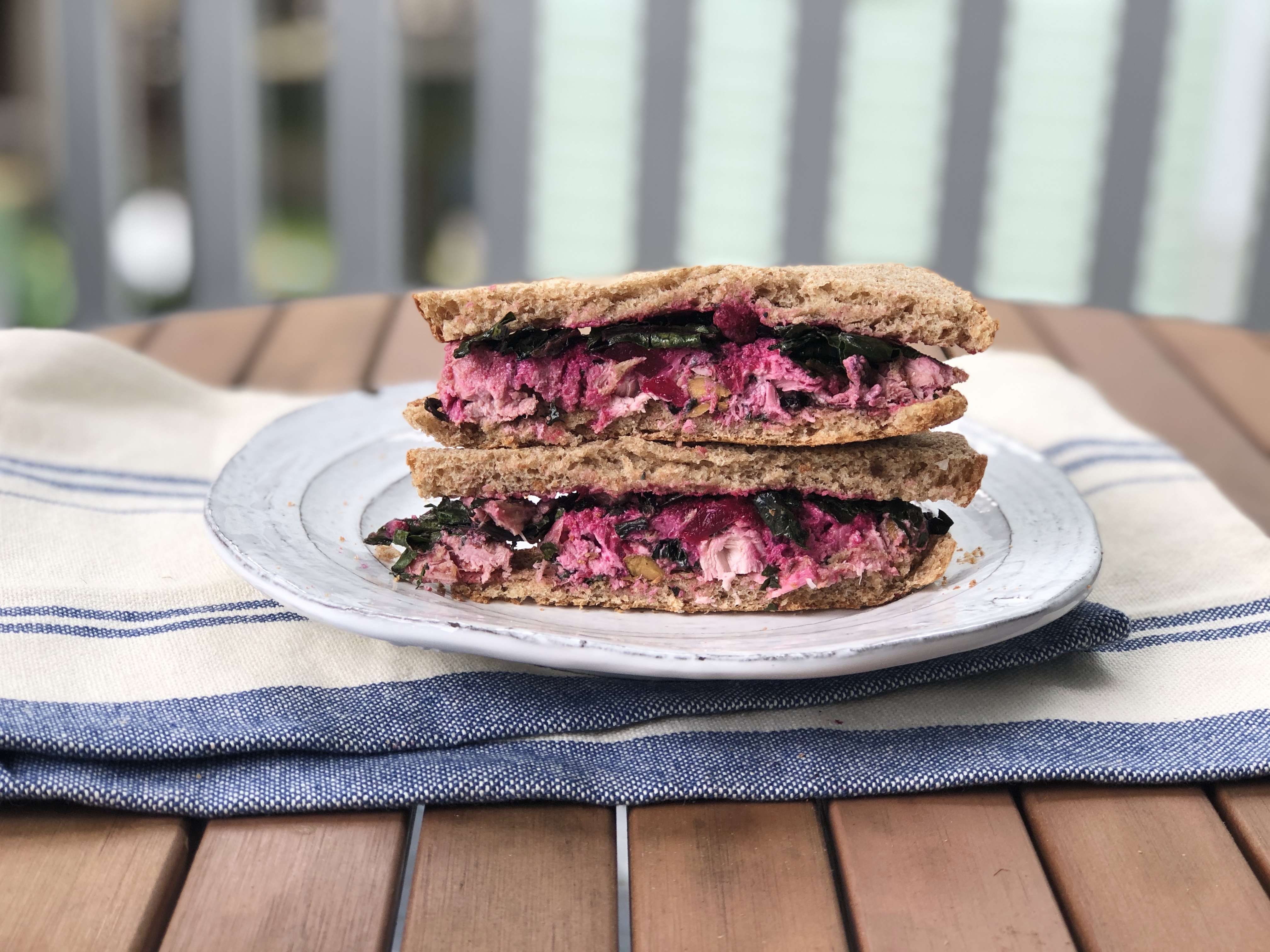 sandwich with beet filling and whole grain bread on a plate outdoors