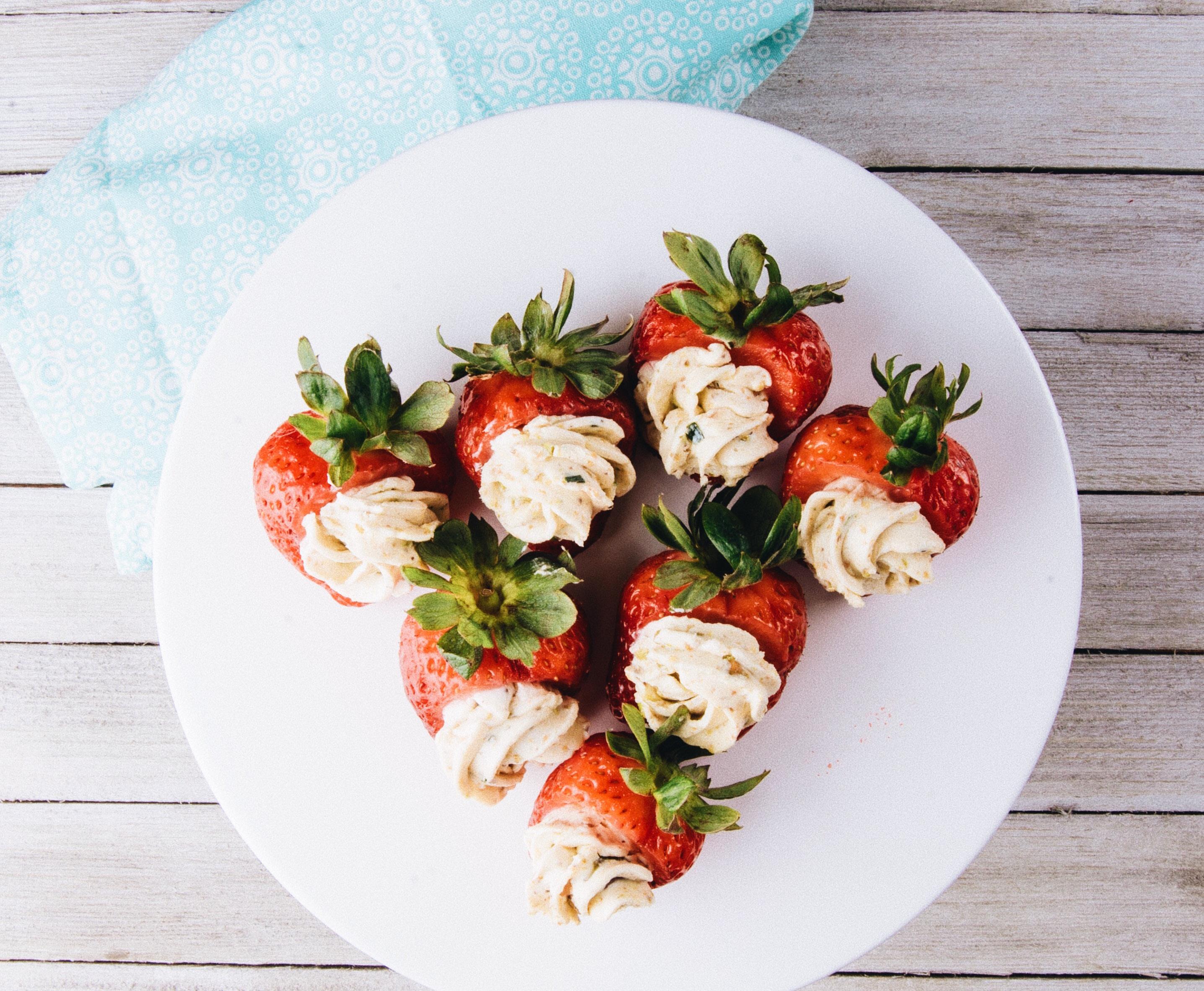 strawberries stuffed with cheese arranged neatly on a white plate