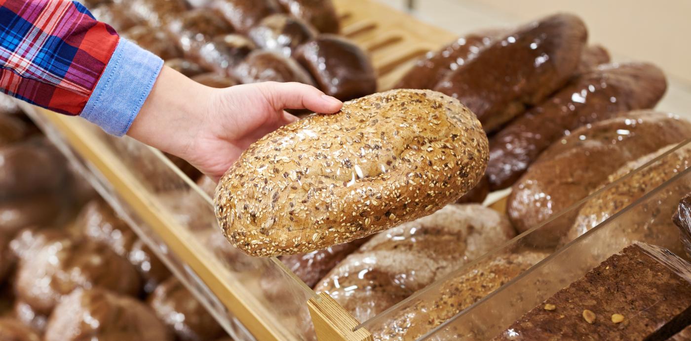 someone holding a loaf of bread in the grocery store