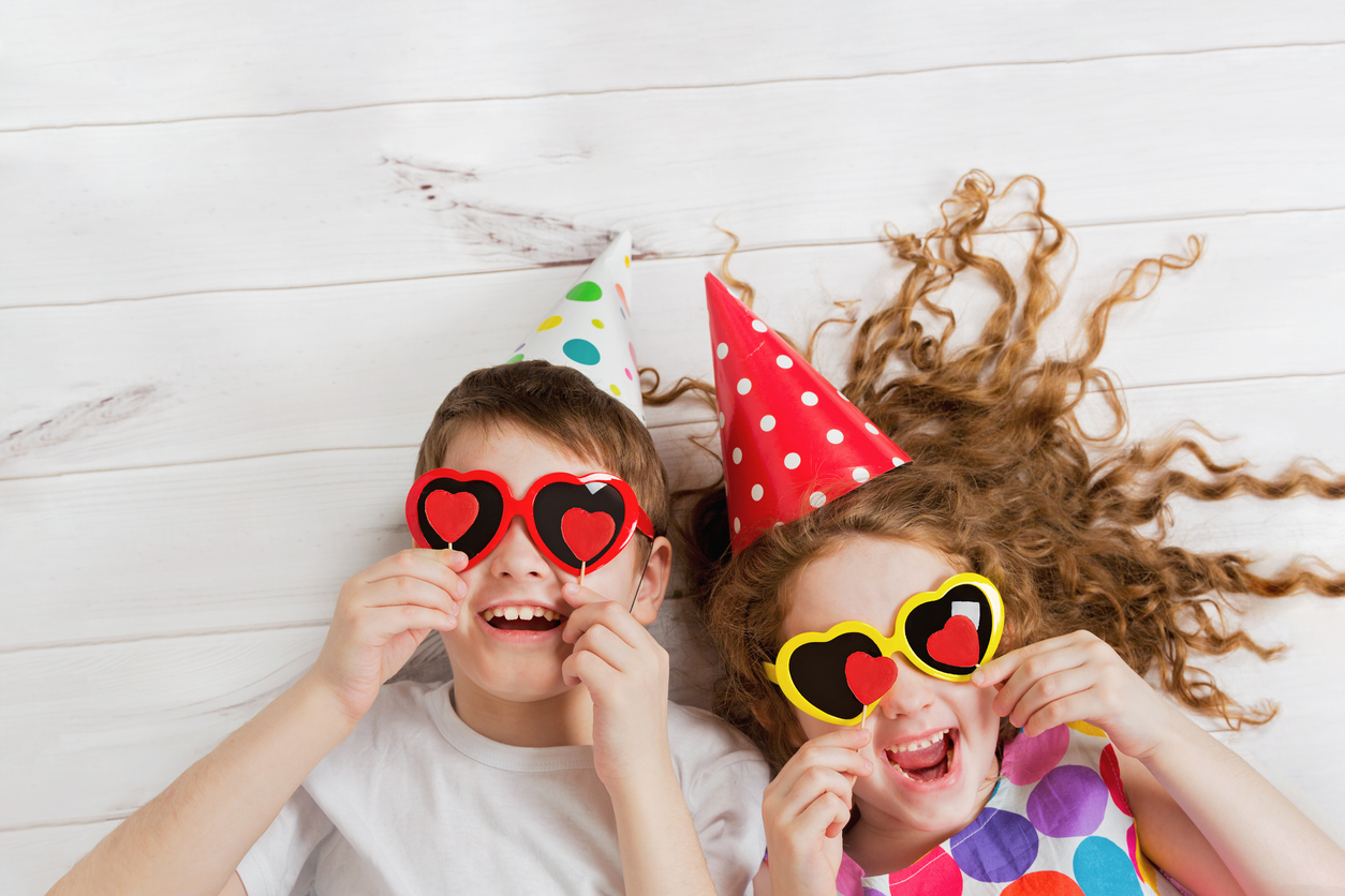 boy and girl laughing with heart sunglasses and party hats