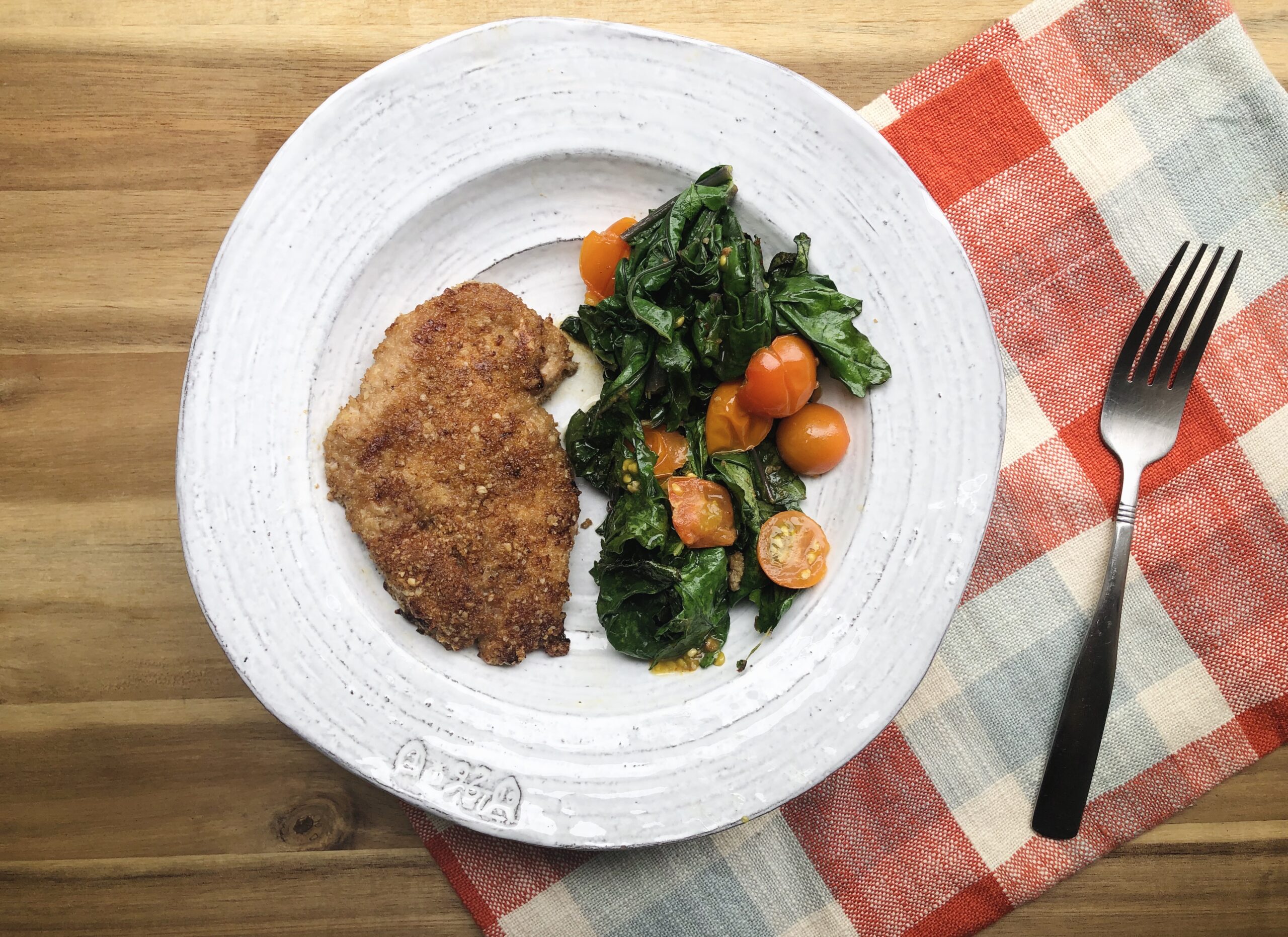 walnut crusted chicken with collards on white plate