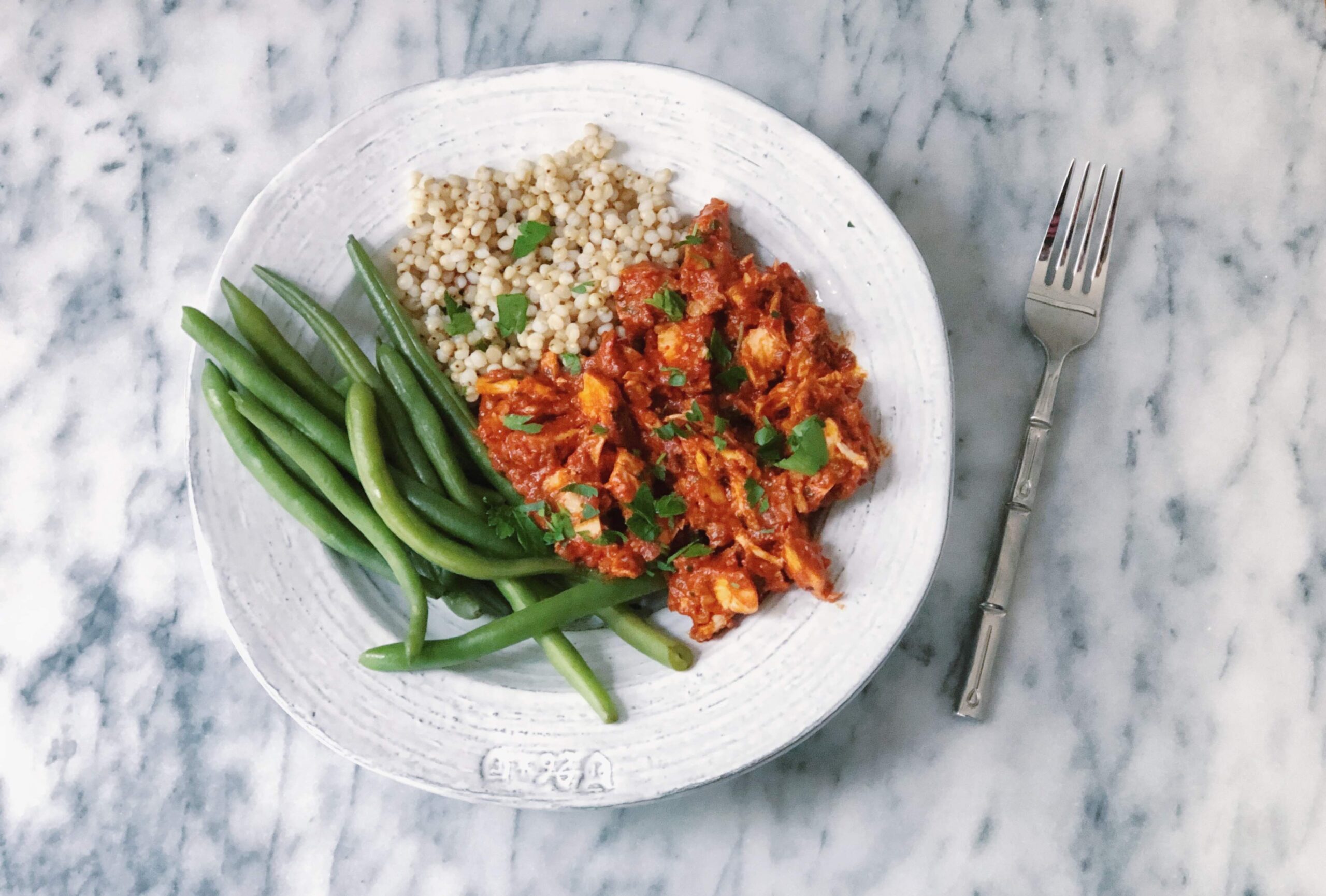 chicken in romesco sauce served atop sorghum and green beans