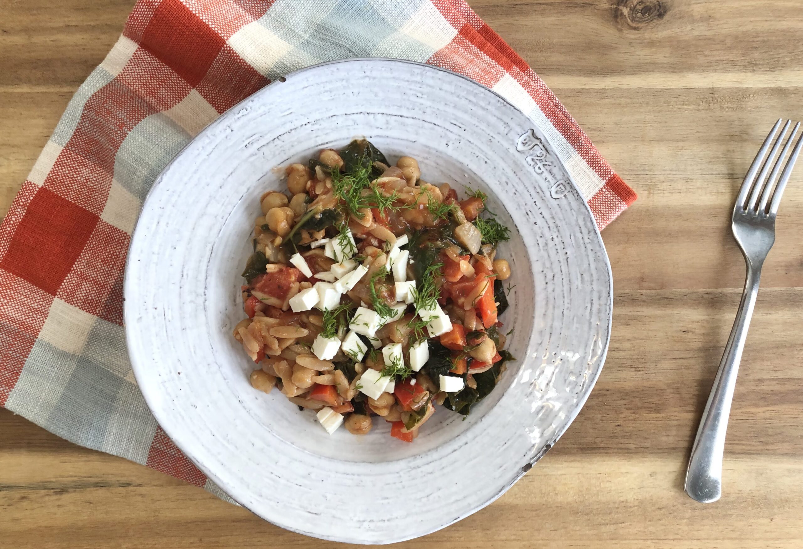 a bowl of orzo pasta and veggies in a white bowl