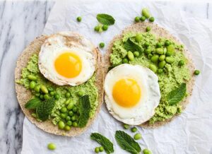 Two tortillas served with a generous layer of eggs and peas, highlighting a vibrant and nutritious meal.