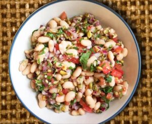 A fresh salad composed of white beans, ripe tomatoes, and parsley, highlighting a nutritious and appetizing meal.