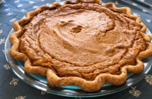 A delicious pumpkin pie resting on a glass plate, highlighting its smooth texture and inviting appearance.