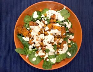 A bowl of fresh spinach salad topped with a light dressing