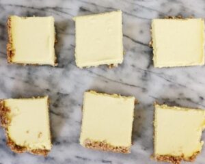 Four squares of cheesecake arranged neatly on a polished marble counter, showcasing their creamy texture and rich color.