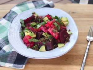 A vibrant bowl of red beet salad featuring creamy avocado slices and a splash of fresh lime