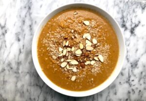 A bowl of soup topped with a mix of nuts and almonds, showcasing a blend of textures and flavors.