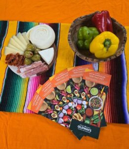 A vibrant spread of Mexican food arranged on a colorful blanket, showcasing various traditional dishes and ingredients.