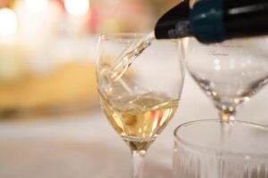 A hand pouring sparkling champagne into a flute glass
