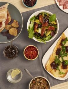 Assorted Mediterranean dishes including salad, flatbread with toppings, and condiments