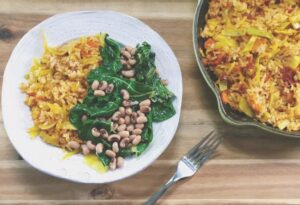 A colorful plate of food with a portion of beans, rice, and fresh spinach