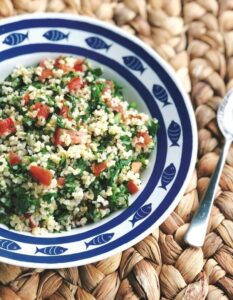 A bowl of couscous salad featuring fresh tomatoes and parsley, garnished for a vibrant presentation