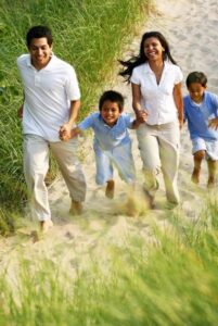 A family joyfully runs through the sand on a sunny beach