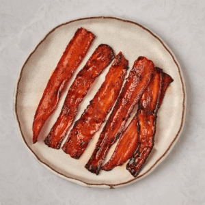 A plate of neatly sliced carrots arranged on a clean white background