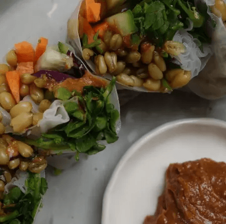 A plate with various food items and a small bowl of sauce