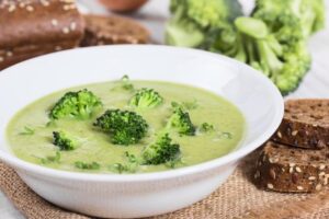 Creamy broccoli soup served in a bowl alongside a slice of crusty bread
