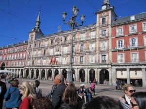 People stroll through a plaza in front of a large building