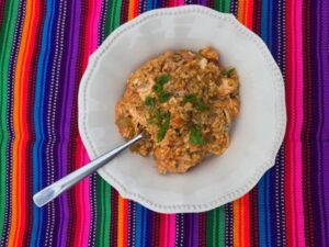 A white bowl with spicy chicken and rice dish