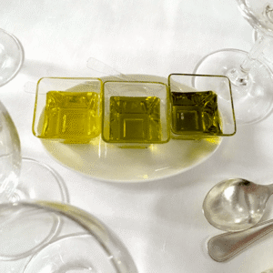 Three small square green glass dishes filled with olive oil
