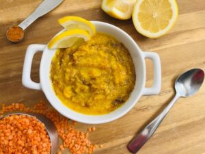 A bowl of lemon and lentil soup garnished with fresh herbs
